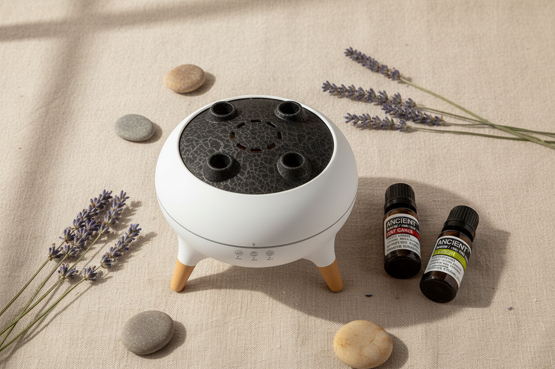 A serene flat lay of Heart Hill Gifts aromatherapy diffuser and essential oil bottles styled with dried lavender and smooth stones on a linen surface