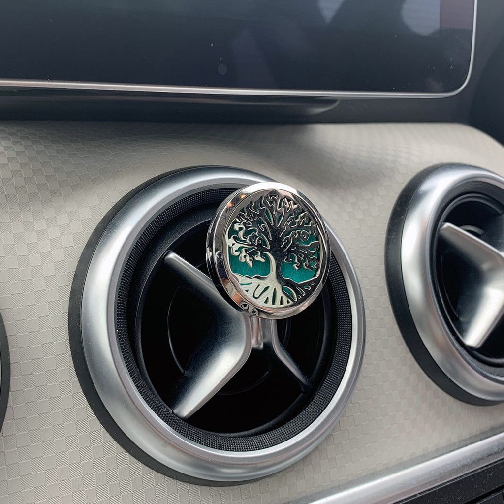 Car air vent with decorative emblem featuring a tree design.