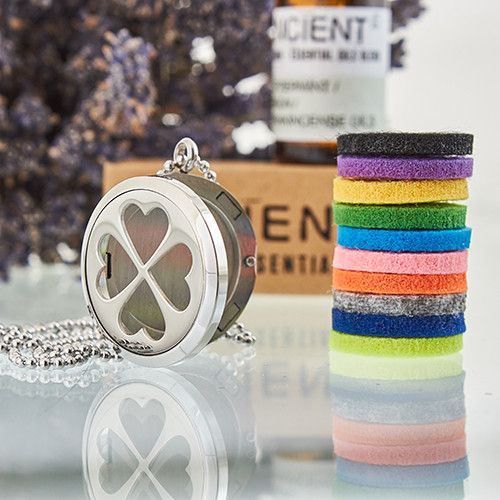 Silver locket with four leaf clover design and felt replacements on a reflective surface.