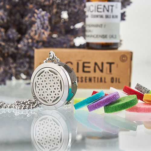 Silver diffuser necklace with essential oil bottle and colorful items in the background