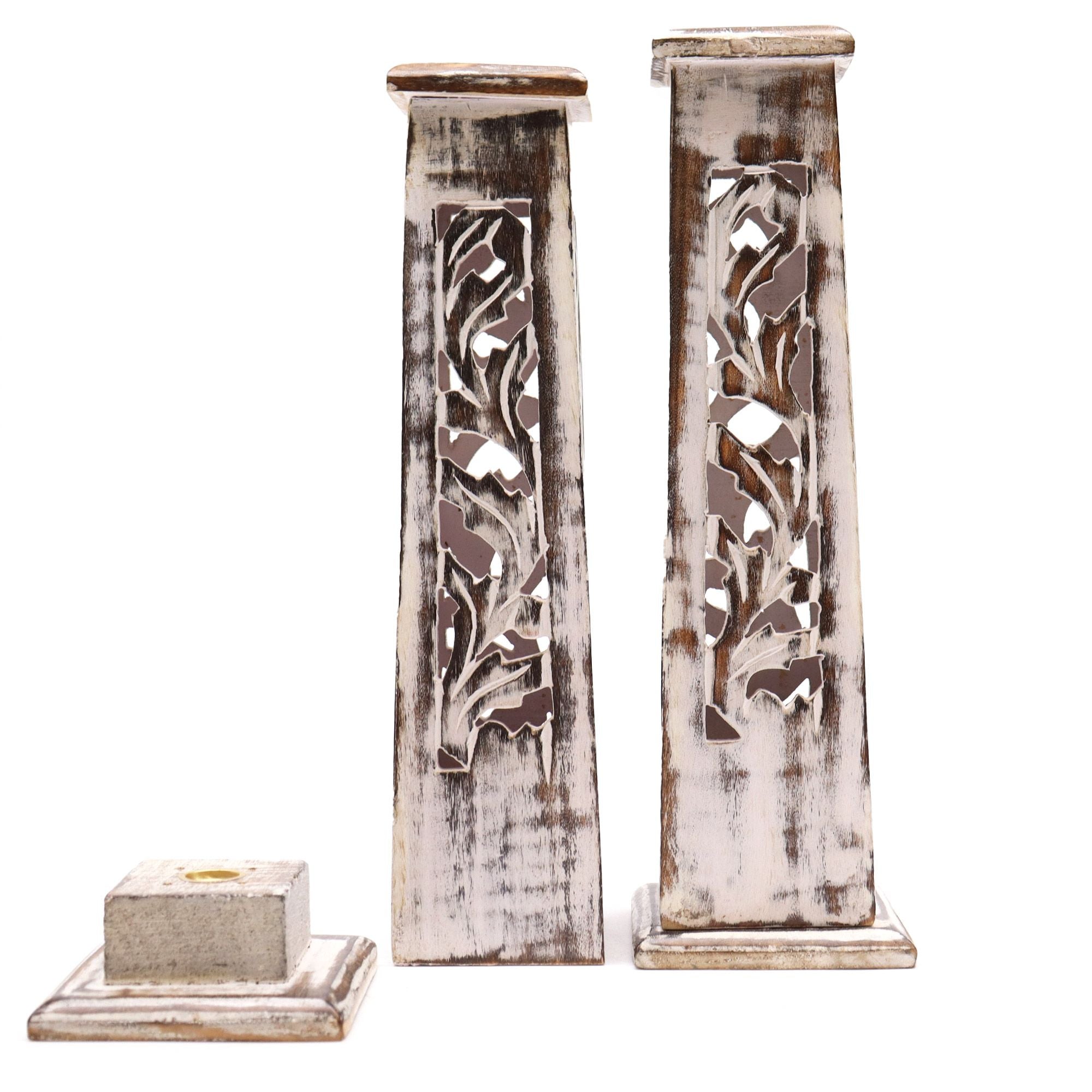 Two decorative wooden incense stick / cone pillars with intricate carvings on a white background