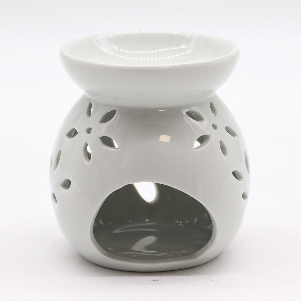 White ceramic oil burner with decorative holes on a white background