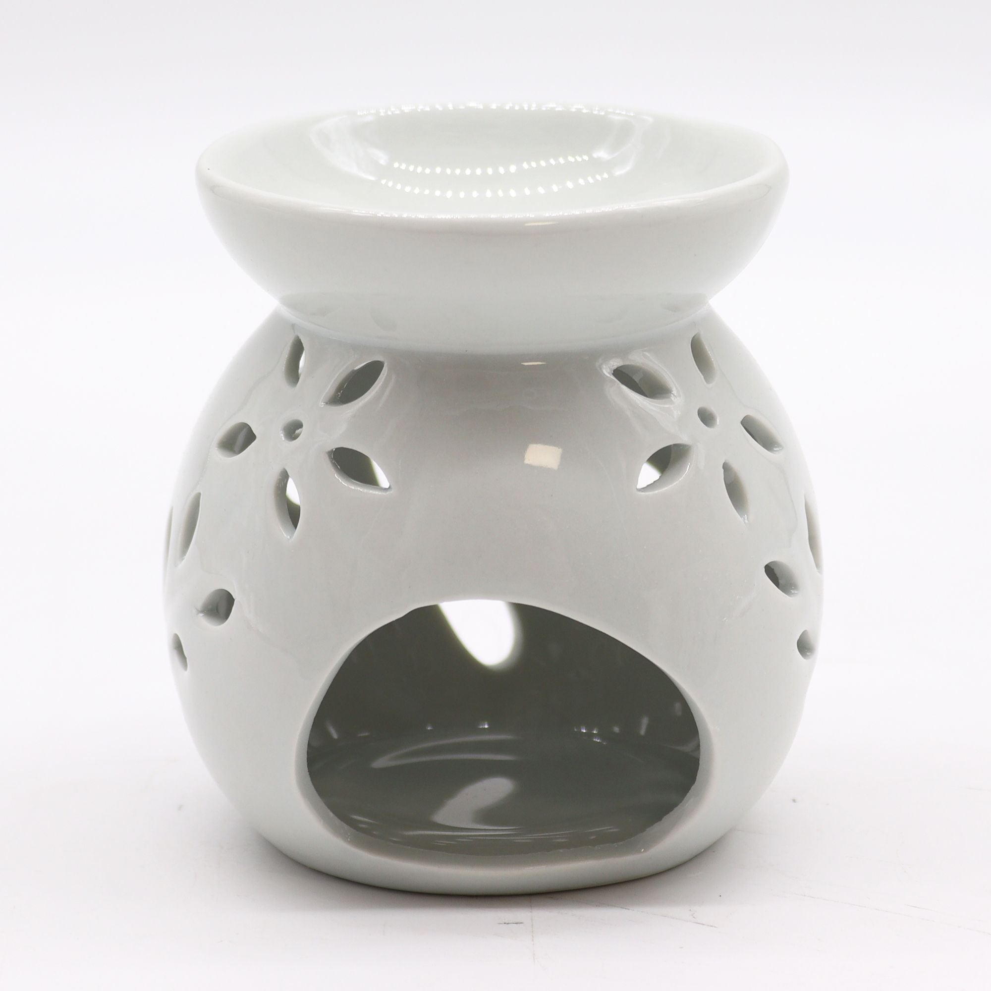 White ceramic oil burner with decorative holes on a white background