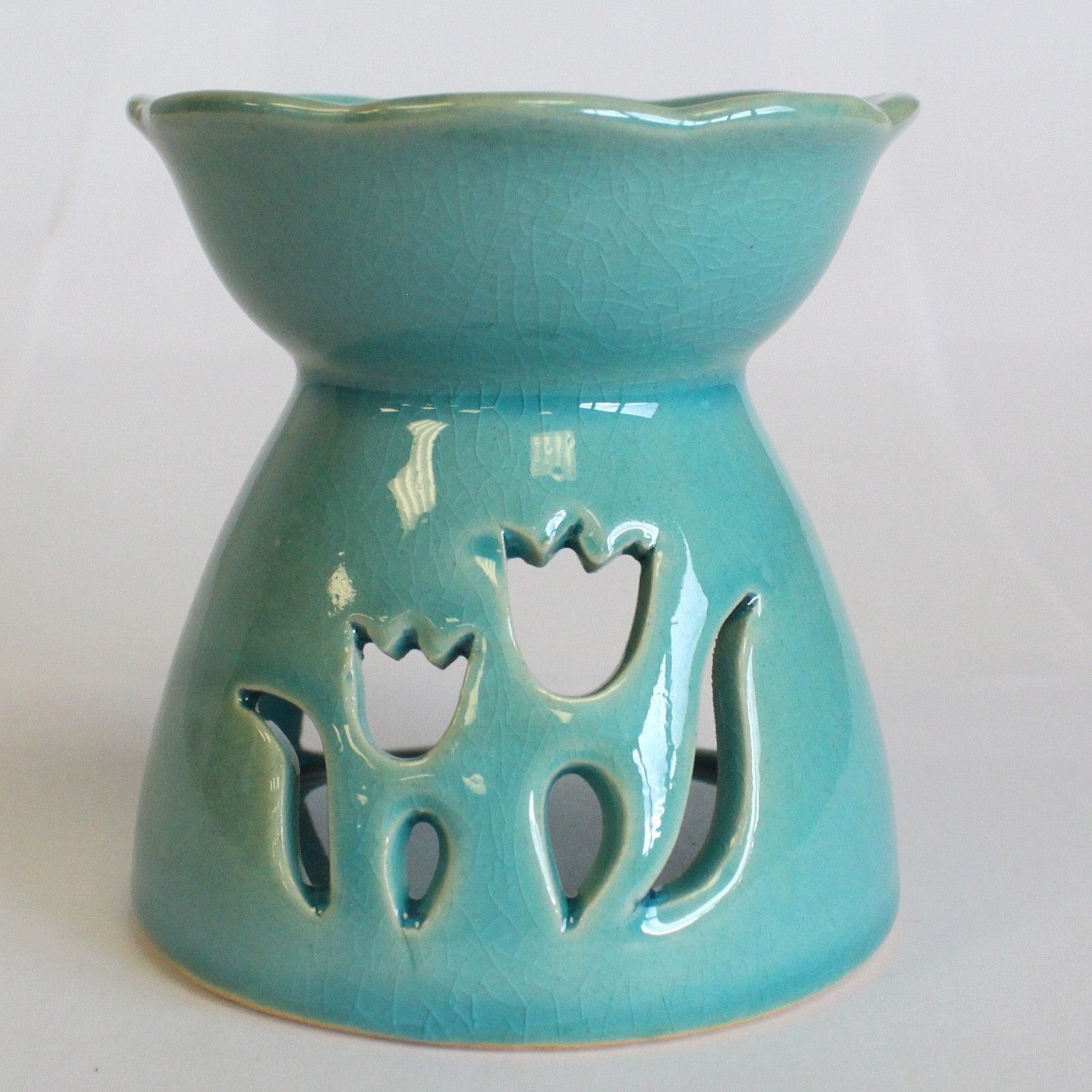 Turquoise ceramic oil burner with tulip designs on a white background