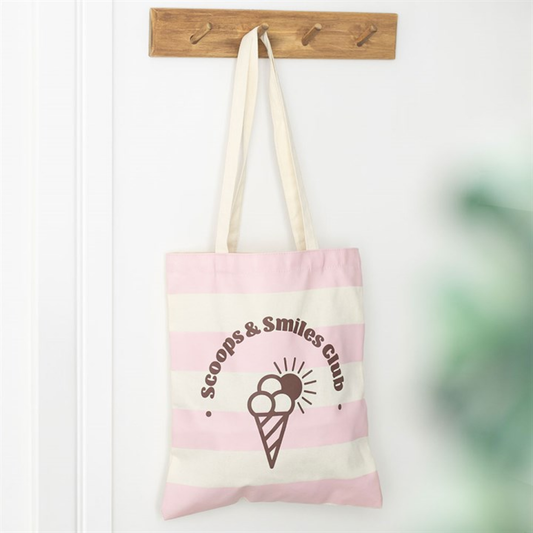 Tote bag with 'Scoops & Smiles Club' design hanging on a wooden hook.
